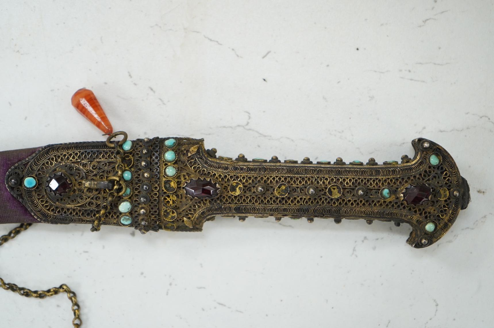 A Late 19th century Hungarian dagger, the hilt and sheath mounts made from filigree gilt silver wire applied with cabochon turquoise and red stones (some missing), blade 13.5cm